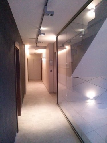 Budynek A - wewnętrzny korytarz z windą, taflami szkła oraz specjalnym oświetleniem.