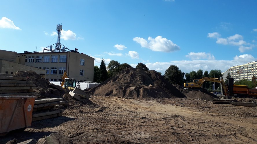 Teren budowy z hałdą ziemi pochodzącą z wykopu pod fundamenty i podziemną halę garażową.