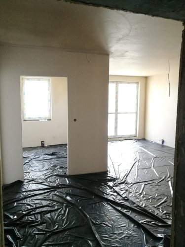 Budynek 4 - wnętrze mieszkania podczas prac wykończeniowych, widoczne szerokie przeszklenie prowadzące na południowy balkon.