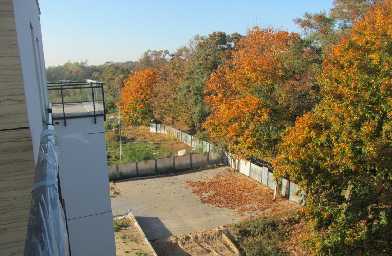 Widok z balkonu budynku B na fragment terenu osiedlowego w sąsiedztwie jesiennego parku.