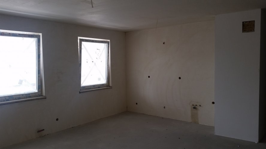 Budynek Delta - wnętrze mieszkania po wykonaniu tynków gipsowych, widoczne instalacje w aneksie kuchennym.
