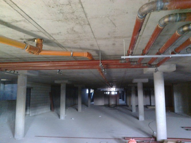 Budynek Charlie - prace na poziomie podziemnej hali garażowej, układanie instalacji wewnętrznych budynku.
