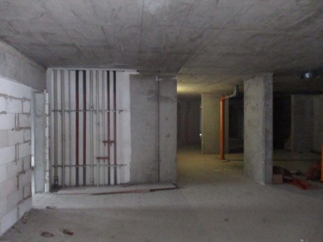 Budynek Delta - podziemna hala garażowa na poziomie parteru, widoczne piony instalacji wodnej i deszczowej.