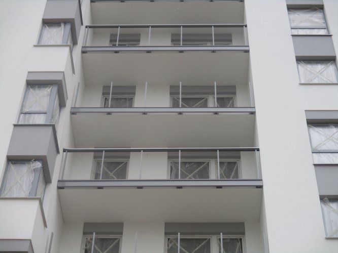 Budynek Charlie - fragment elewacji, widoczne duże balkony oraz balustrady ze szklanymi wypełnieniami.