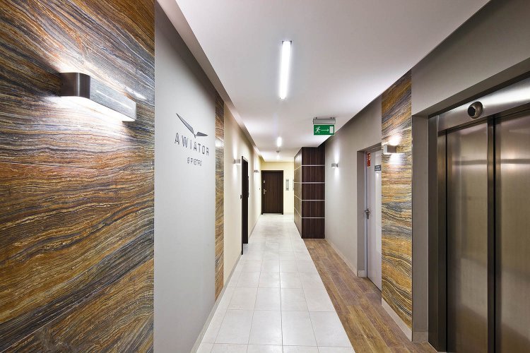 Awiator - wewnętrzny korytarz z dwoma nowoczesnymi windami, zaaranżowny przy użyciu wysokiej jakości materiałów.