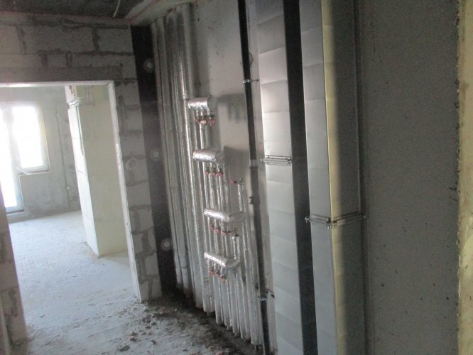 Budynek Delta - szachty instalacji wodnej i CO zlokalizowane na korytarzu, w tle widoczne okna mieszkania.