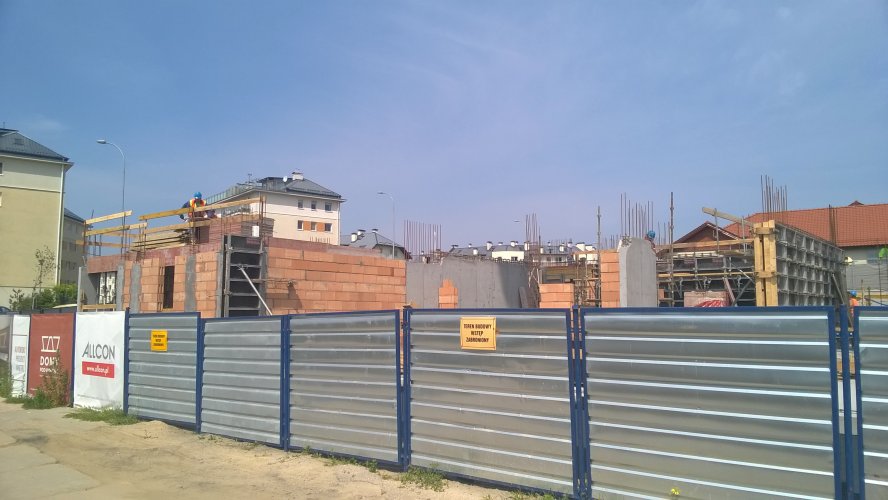 Ogrodzenie budowy od strony południowej. Widoczne ściany parteru powstającego budynku 1.