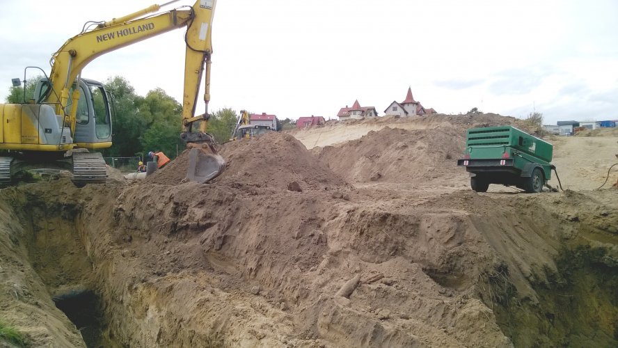 Koparka wykonująca wykopy w celu ułożenia podziemnej infrastruktury osiedla.