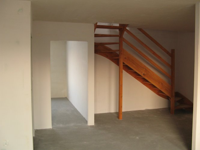 Wnętrze mieszkania 2-poziomowego, drewniane schody prowadzące z poziomu dolnego na poddasze.