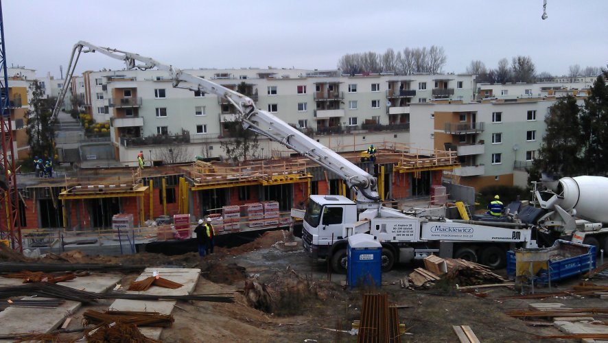 Budynek 1 - wylewanie betonu na stropie nad parterem, elewacja południowa budynku oraz osiedle WAM w tle.