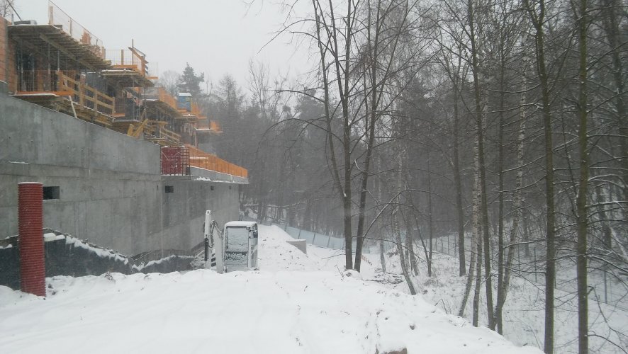 Budynek 6 - fragment elewacji południowej, widoczny mur oporowy z tarasami od strony lasu. Prace na poziomie piętra 2.