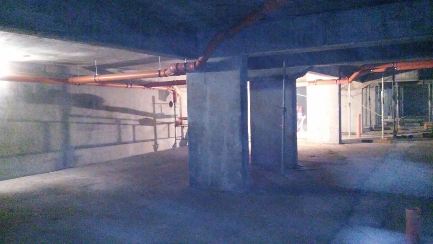 Budynek 2 - podziemna hala garażowa z szerokimi miejscami dla samochodów, montaż rur kanalizacji pod sufitem.