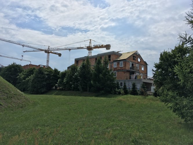 Budynek 1 - narożnik płónocno-zachodni wśród zieleni drzew od strony terenu ujęcia wody dla Gdańska. Widoczne prace na poziomie dachu.